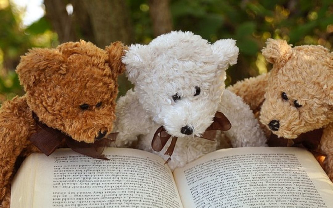 Tre teddybjørner leser eventyrbok sammen i skogen. Foto: Pixabay